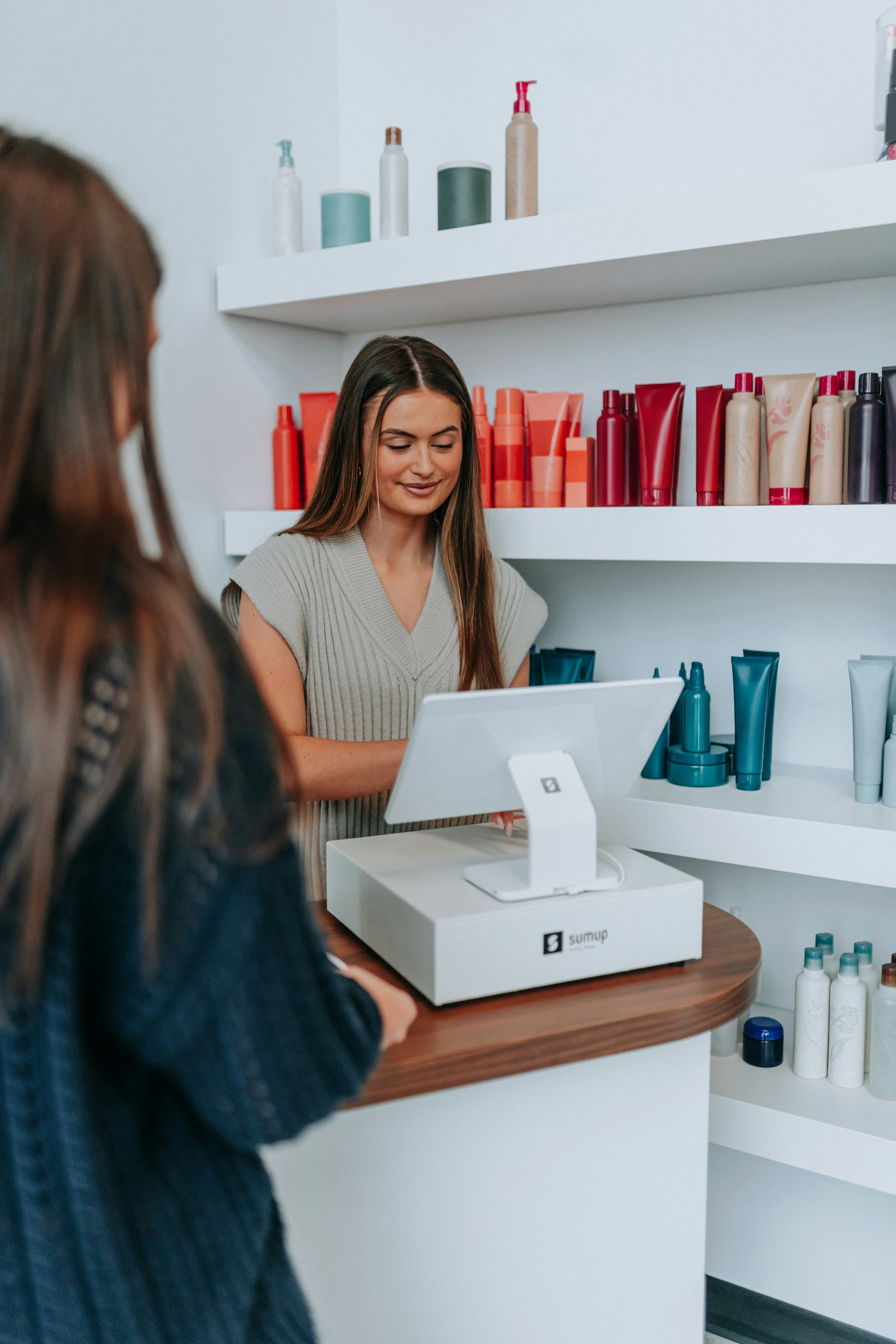 A hairstylist checks out a customer at the register